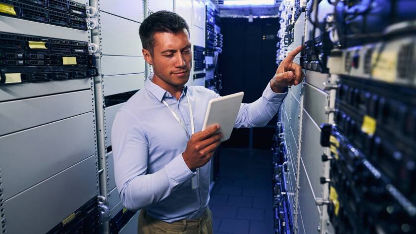 IT technician consulting tablet computer during preventive maintenance