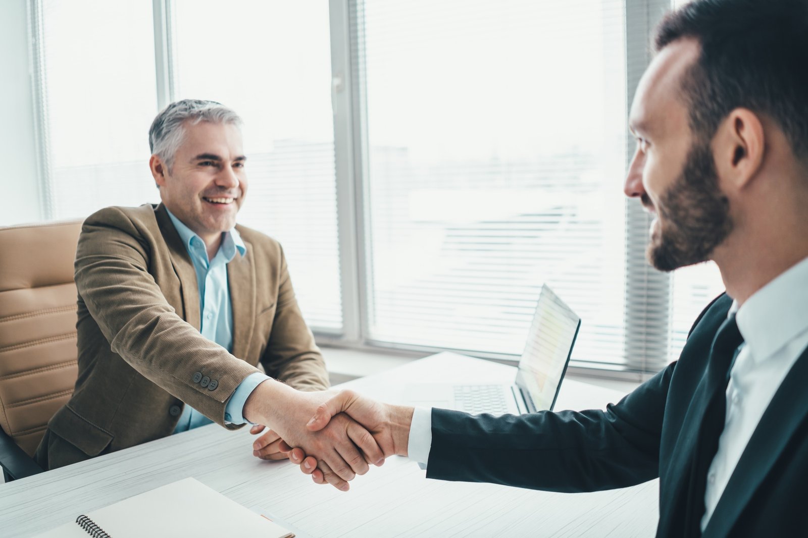 The happy businessmen handshaking above the office table